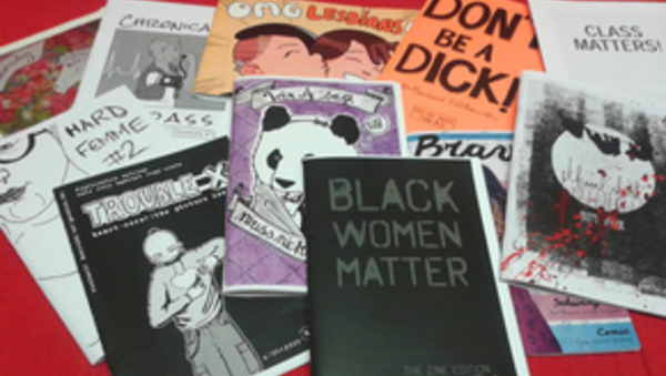 Es sind verschiedene Flyer und Heftchen mit Titelsprüchen zu sehen, die für mehr Offenheit und gegen Diskriminierung stehen. Beispielsweise "Black Women Matter" oder "OMG Lesbians".