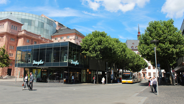 Ein Geschäft mit einer Bushaltestelle und dem Theater im Hintergrund
