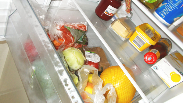 Ausschnitt aus einem Kühlschrank. Unten ein Gemüsefach mit verschiedenem Obst und Gemüse. Darüber ein Fach mit Marmelade,Butter, etc.