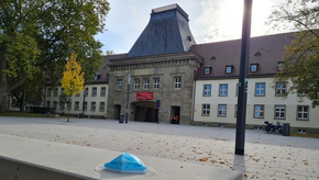 Vor dem Eingang der JGU Mainz liegt eine OP-Maske auf einer Bank.