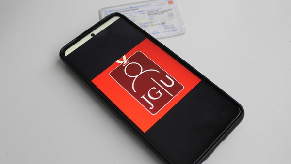 Ein Smartphone mit dem "JGU Ausweise" Appfoto und ein Semesterticket im Papierformat