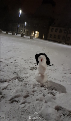 Bild von einem kleinen Schneemann mit Mütze auf dem Vorplatz des Campus