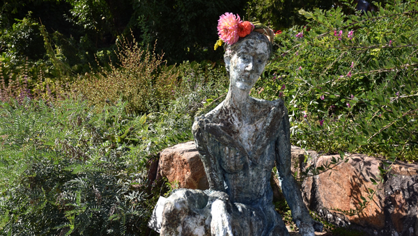 Eine Statue einer Frau, der Blumen auf den Kopf gesetzt wurden.