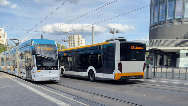 Zu sehen sind eine Straßenbahn und ein Bus der Mainzer Mobilität. Die Haltestelle ist Hbf West / Taubertsberg Bad + Spa.