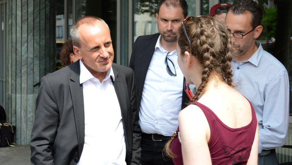 Konrad Wolf (Minister für Wissenschaft, RLP) unterhält sich mit einer Demonstrantin. Neben ihnen stehen zwei weitere Männer im Anzug. 