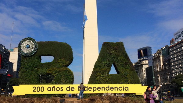 Der Obelisco auf der 9 de Julio in Buenos Aires. Davor ein "B" und ein "A" aus einer Hecke geschnitten, dazwischen die argentinische Flagge.