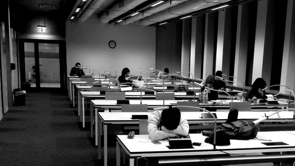 Schwarz-weiß: Einige letzte Studierende in der GFG-Bibliothek. Es ist spät, einer hat schon den Kopf auf den Tisch gelegt und scheint zu schlafen... oder zu verzweifeln.