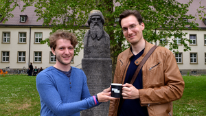 zwei Menschen und eine Tasse mit Gutenbergstatue im Hintergrund