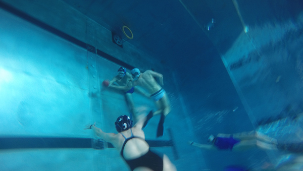 Gruppe von Studenten unter Wasser ringen um einen Ball