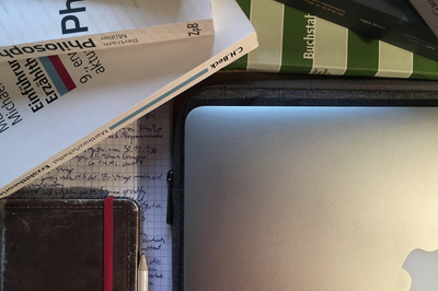 Arbeitsplatz bei Hausarbeiten: Lehrbücher, ein Laptop, ein Notizbuch erleuchtet durch eine Schreibtischlampe.