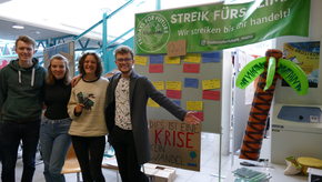 Vier Studierende präsentieren ihren Stand von "Students for Future Mainz", dessen Logos in Grün gehalten sind.