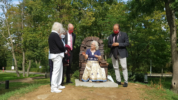 Prof. Dr. Elisabeth Gateff sitzt in der Sessel-Skulptur, die aus bronzenen Büchern besteht. Sie unterhält sich mit Liesel Metten, Gabriele Ptok, Prof. Dr. Georg Krausch und Prof. Dr. Stephan Jolie.