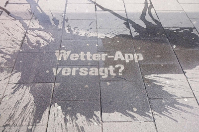 Ein nasser Boden, auf dem der Text "Wetter-App versagt?" steht.