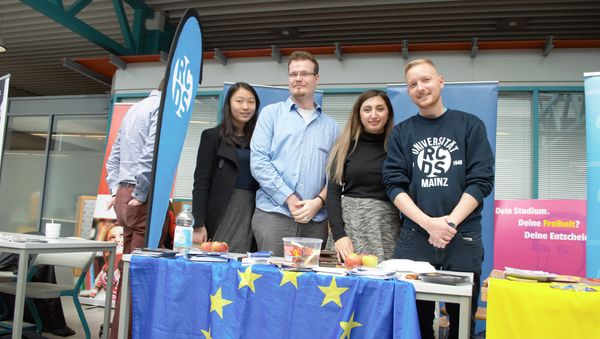 Vier Mitglieder der politischen Hochschulgruppe RCDS stehen hinter ihrem Messestand, an dem u.a. eine Europaflagge den Tisch vor ihnen bedeckt.
