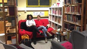 Zwei Mitarbeitende der Fraunebibliothek der Uni Mainz sitzen auf einem Sofa in der Frauenbibliothek.