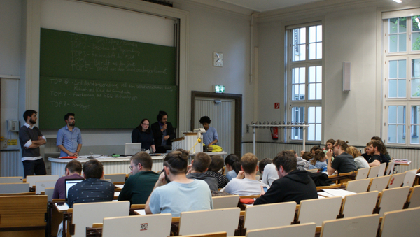 Ein besetzter Hörsaal, vorne stehen mehrere Referenten.