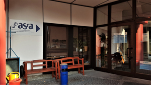 Das Bild zeigt das Büro des AStA im Staudingerweg von außen: Vor der Tür steht eine Bank, darüber und an der Tür selbst ist sein Logo zu sehen.