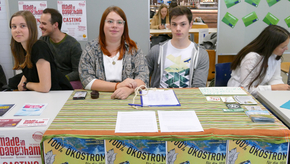 Zwei Studierende sitzen vor einem Tisch mit Flyern und einer Petition für ihre Initiative "100% Ökostrom".