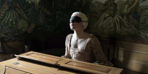 Eine Frau mit verbundenen Augen sitzt an einem Klavier
