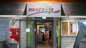 Über einer offenen Eingangstür hängt ein Schild, auf dem "Mensaria" steht.
