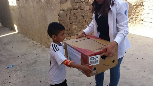 ein kleiner Junge nimmt einen Karton einer Frau entgegen