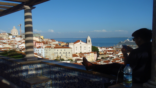 Ausblick über die Stadt Lissabon mit einer Person, die links im Bild sitzt.